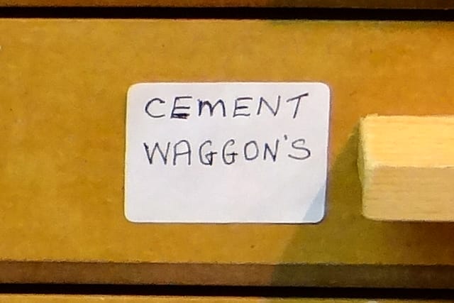 A drawer label in his hand reading “CEMENT WAGGON’S”.