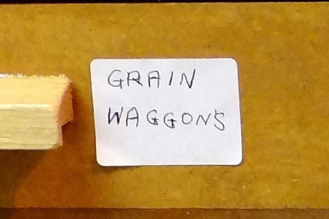 A drawer label in his hand reading “GRAIN WAGGON’S”.
