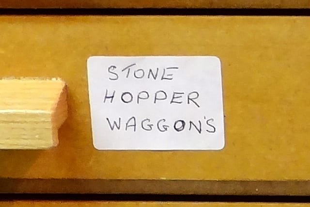 A drawer label in his hand reading “STONE HOPPER WAGGON’S”.